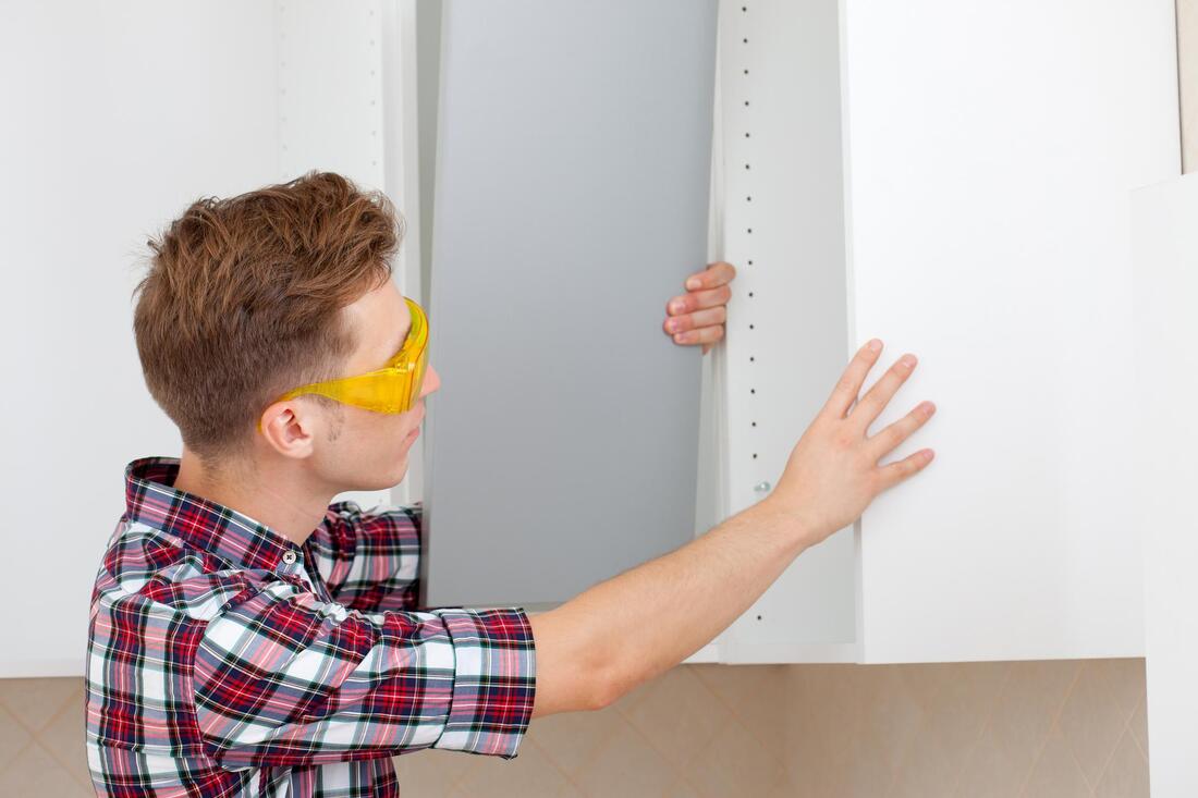 worker in glasses installing the cabinet